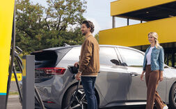 Zwei Personen, die ein Elektroauto an einer ÖAMTC ePower-Ladesäule anschließen, um den Akku aufzuladen.