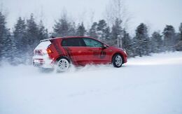 Ein rotes Auto auf Schneefahrbahn.