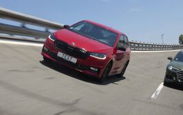 Ein rotes und ein grünes Auto fahren nebeneinander auf einer Teststrecke.