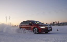 Rotes Auto fährt auf Schneefahrbahn bei Sonnenaufgang